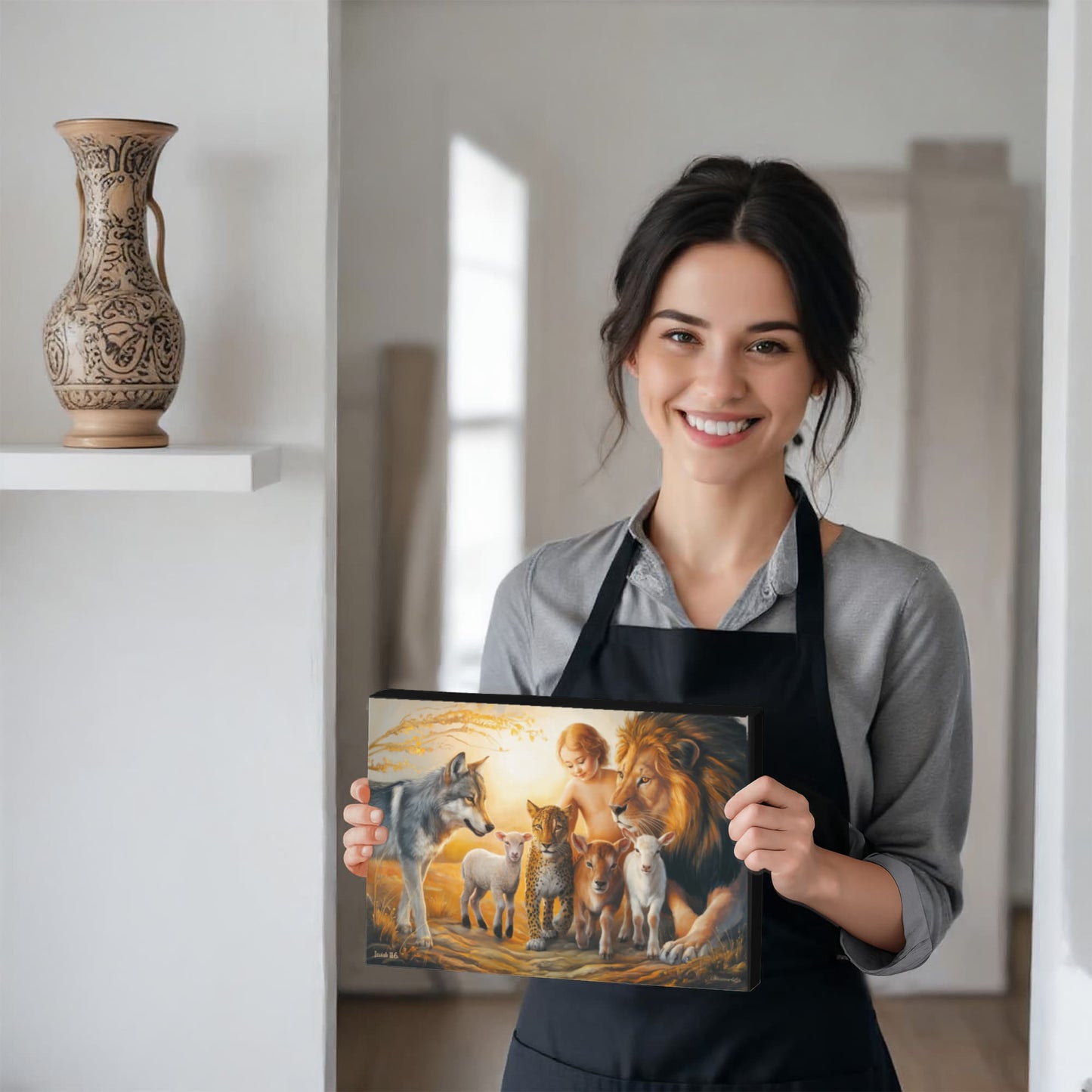 Woman holding a canvas art with a colorful design of a child and animals, wearing a black apron.