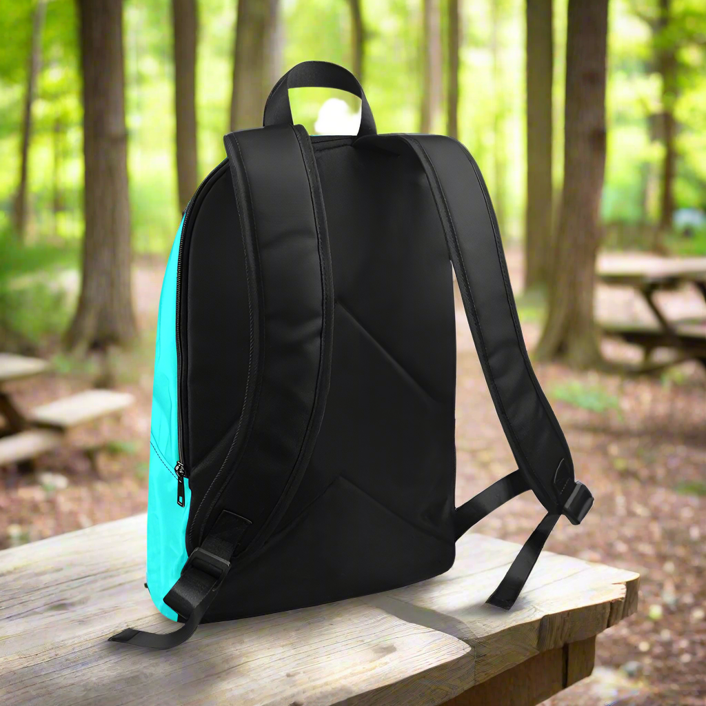 Black backpack with a turquoise backrest on a wooden table in a forest setting