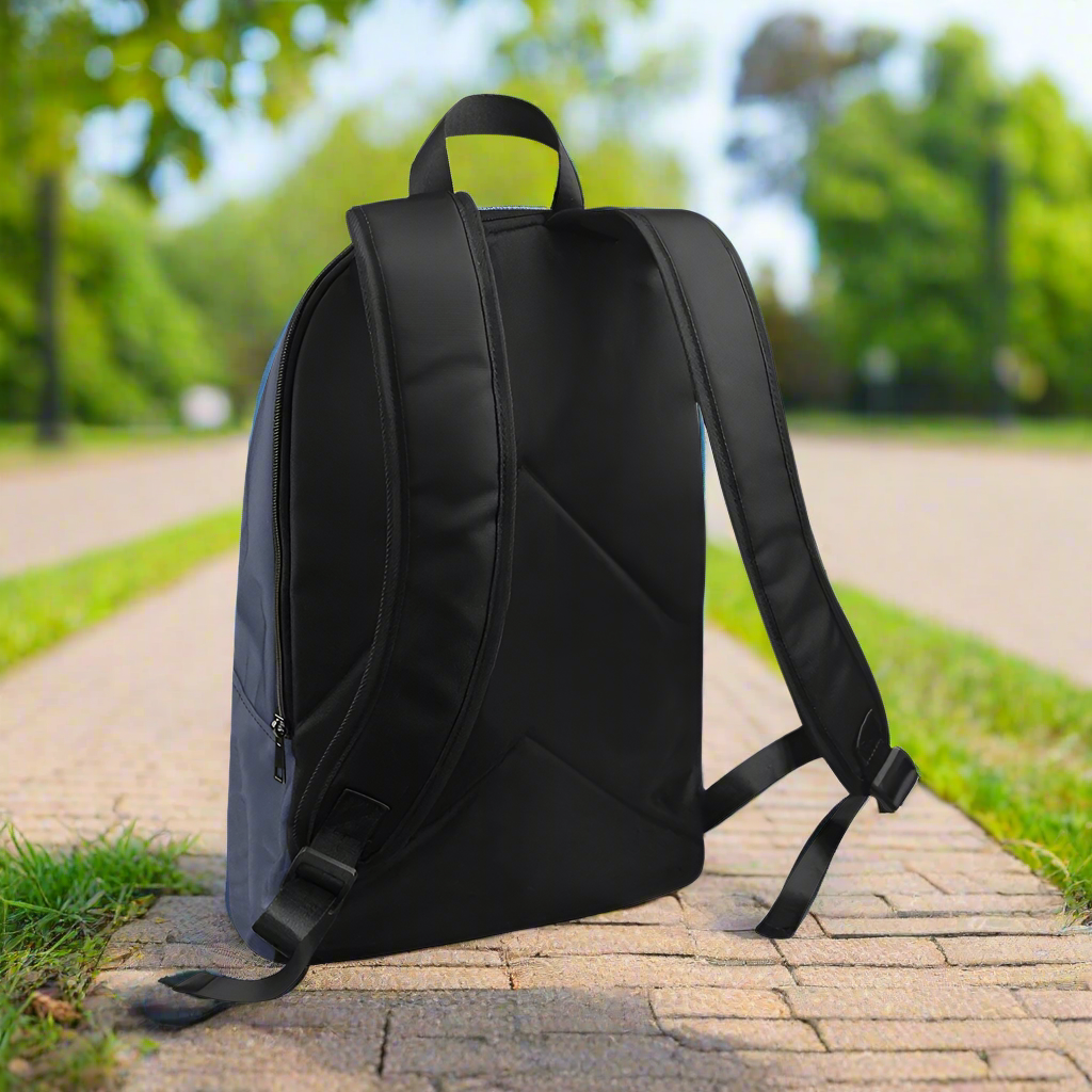 Black backpack on a paved path with greenery in the background