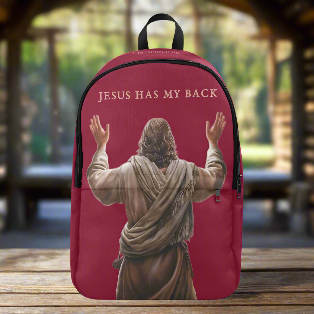 Pink backpack with a graphic of Jesus with arms outstretched and 'Jesus Has My Back' text, placed on a wooden surface.