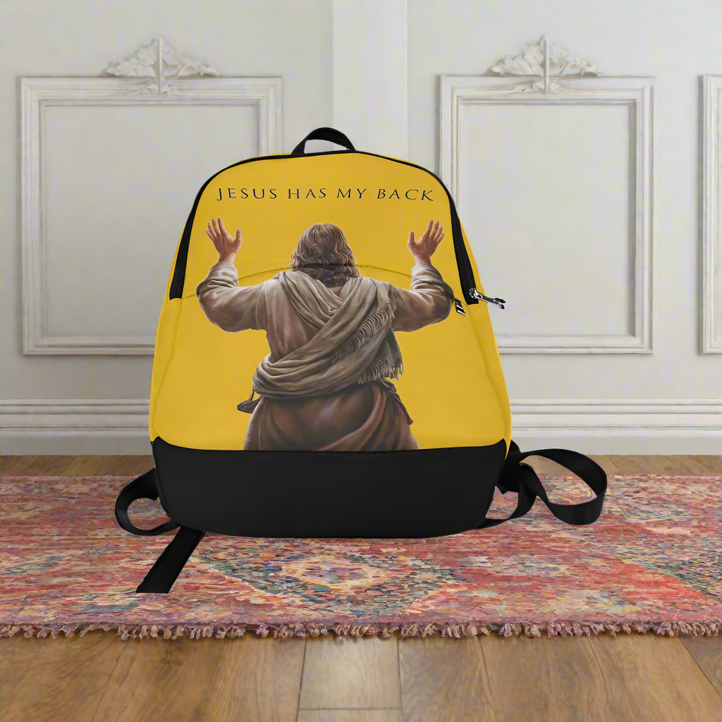 Backpack with a graphic of Jesus in robes and 'Jesus Has My Back' text on a yellow background, placed on a wooden floor.