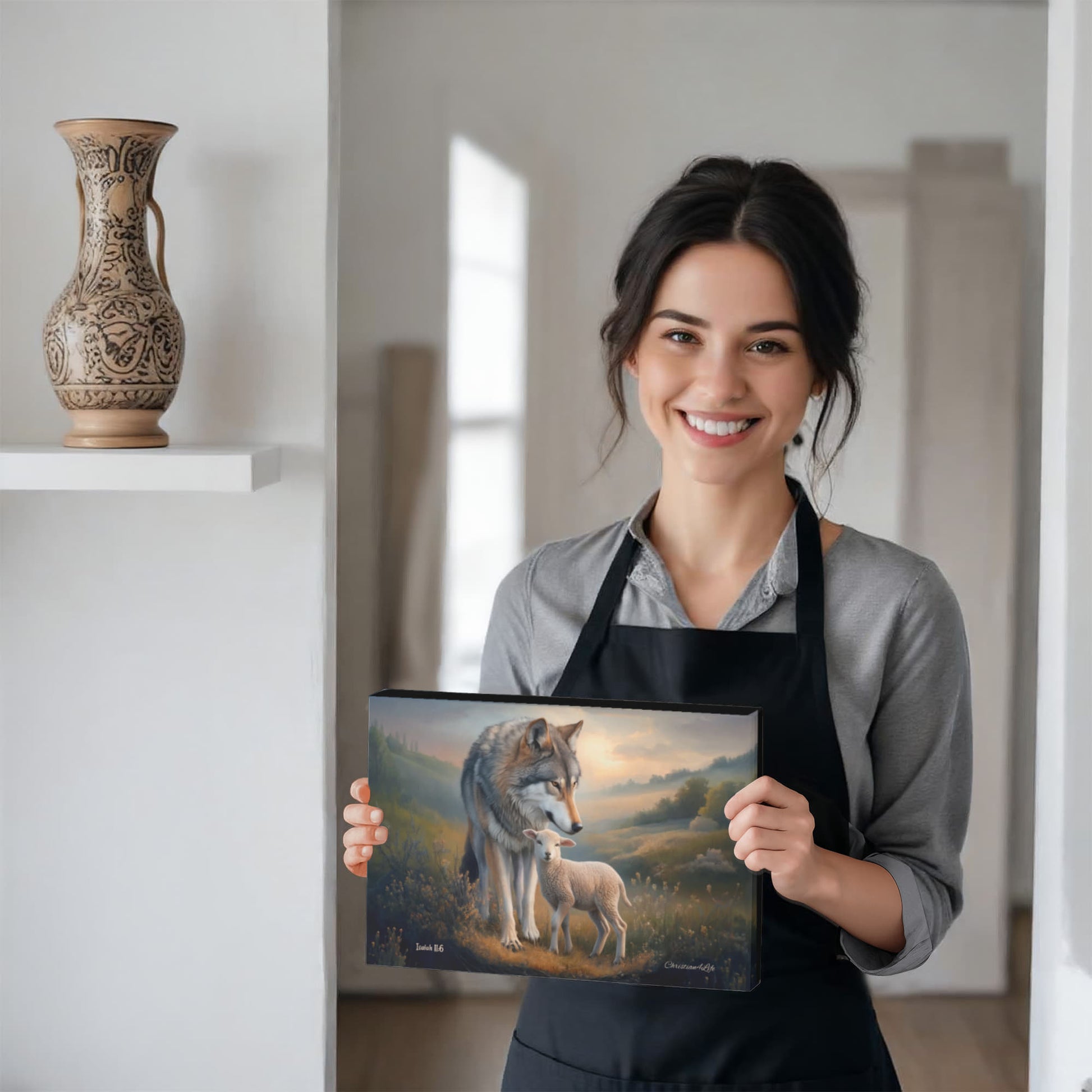 Woman holding a canvas with a wolf and lamb design, wearing a black apron.