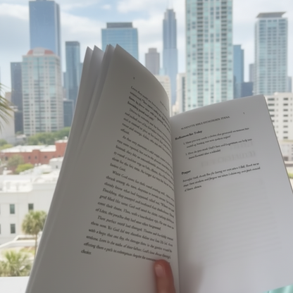 Open book held by a hand with a blurred outdoor background