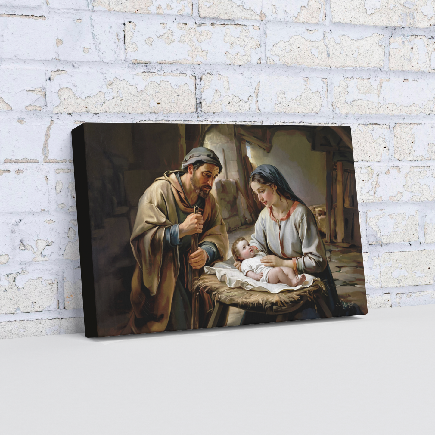 Canvas print of a religious scene with baby Jesus, Joseph and Mary, displayed against a brick wall.